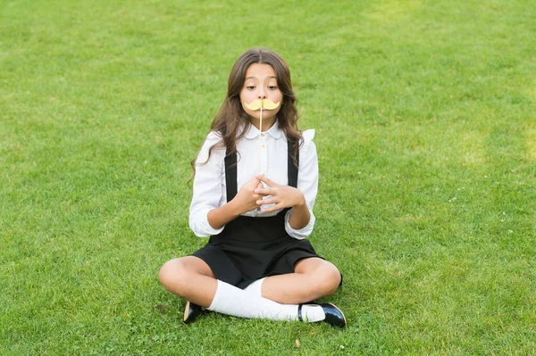 Pronto para a festa da escola. Criança segurar bigode adereços grama verde. Menina pequena com adereços de fotocabine no pau. adereços do partido e acessórios. Material perfeito para a celebração de despedida. Férias de verão — Fotografia de Stock