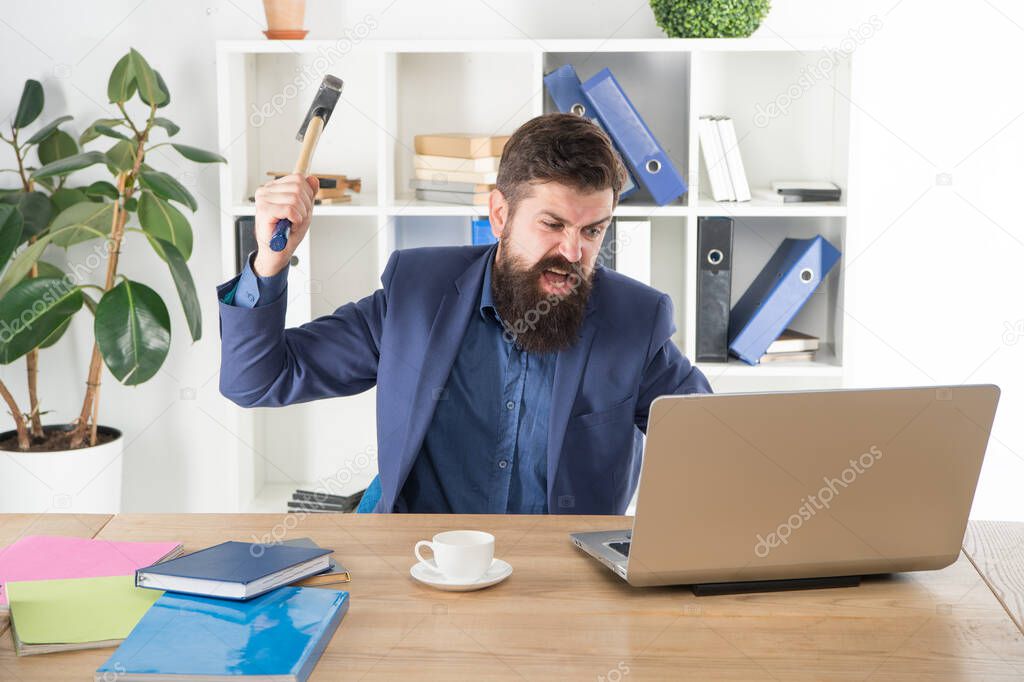 overworked man crush laptop with hammer. frustrated computer user. businessman express anger. ready to smash. Office life makes him crazy. Slow internet connection. dealing with error