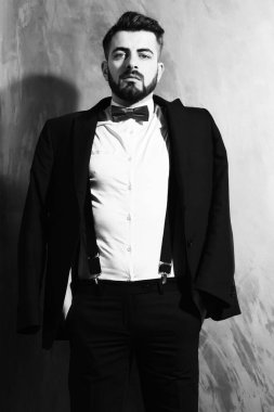 Stüdyo duvarında ciddi bir yüzü olan sakallı bir adam.