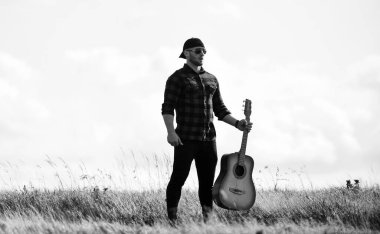 Müziği çal, enstrümanı değil. Batı kampı ve yürüyüş. Hipster modası. Mutlu ve özgür. Country müzik şarkısı. Akustik gitaristli kovboy adam. Kareli gömlekli, gitarlı seksi adam.