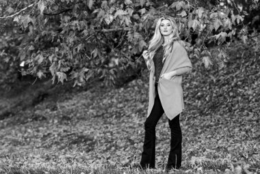 Rahat ve rahat. Hafta sonu için samimi kıyafet fikirleri. Sevimli sarışın kız, sıcacık ve rahat bir elbise içinde sonbahar arka planında poz veriyor. Kadın gün batımında yürür. Sonbahar için rahat kıyafetler.