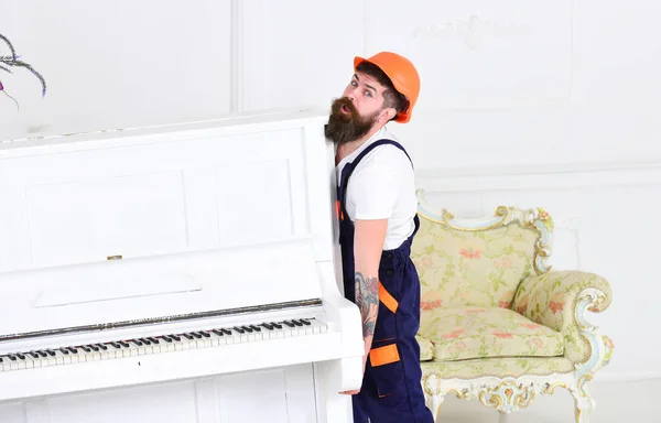 Tipo agotado moviendo piano pesado aislado sobre fondo blanco. Cansado de mover en el lugar de trabajo. Concepto de renovación del hogar — Foto de Stock