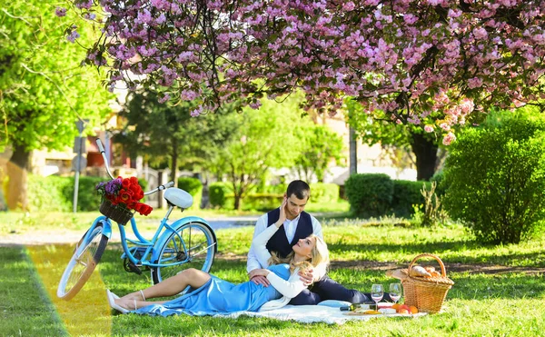 My couple. family relationship and friendship. summer holiday trip. girl and man under sakura. couple in love drinking wine during romantic dinner in park. picnic of couple in love at vintage bike