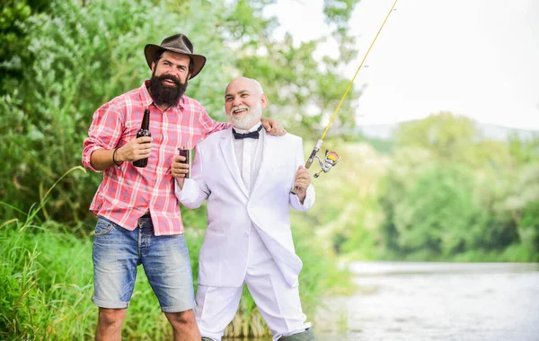 Celebrando el éxito. pasatiempo y actividad deportiva. hombre maduro pescador celebrar la jubilación. fin de semana familiar de verano. padre e hijo pescando. dos pescadores con cañas de pescar. hombre de negocios retirado. amistad —  Fotos de Stock