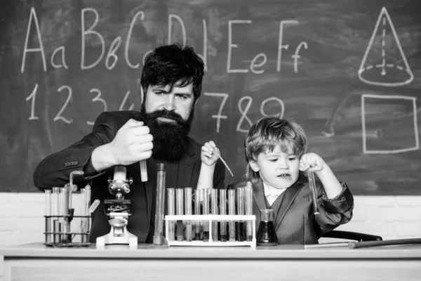 Laboratory test tubes and flasks with colored liquids bearded man teacher with little boy. laboratory research and development. father and son child at school. Chemistry experiment. Pushing Limits
