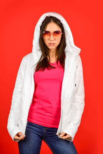 Női divat modell. Divatruha. Rózsaszín szemüveg. Nyugodj meg és vegyél fel hűvös szemüveget. Aranyos lány motorháztető kabát piros háttér. A divatnak tükröznie kell, hogy ki vagy. A nők szeretik a tavaszi időjárást — Stock Fotó