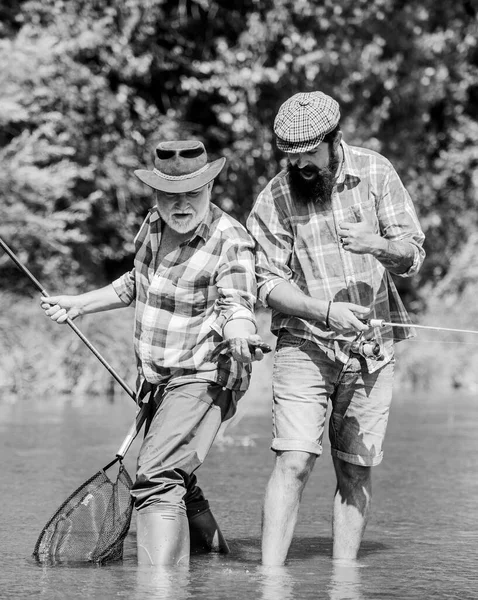 Teamwerk. Vader en zoon vissen. Zomers weekend. Volwassen visser. hobby en sport. Forel aas. mannelijke vriendschap. Familie binding. twee gelukkige visser met hengel en net — Stockfoto