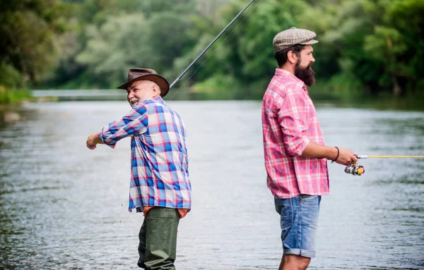 夏の週末。平和的な活動。いいキャッチだ。ロッドとタックル。漁具。漁師のおじいちゃんと大人の男の友人。漁師の家族だ。趣味スポーツ活動。父と息子の釣り — ストック写真