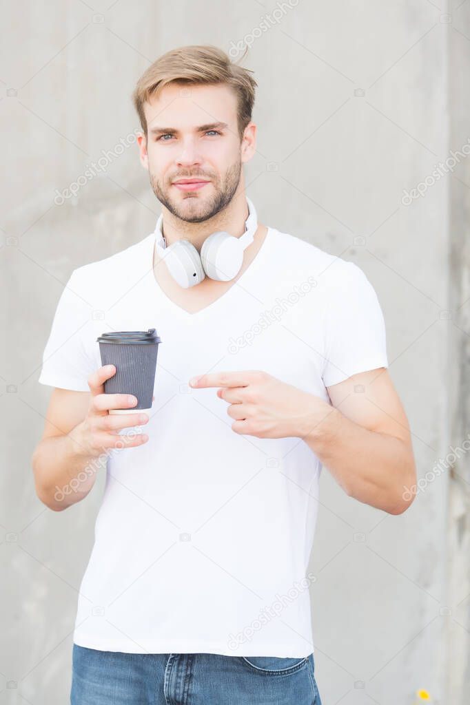 Make your go-to coffee order. Handsome man point at coffee cup outdoors. Young guy drink coffee in morning. New technology. Modern life. Enjoying coffee and music