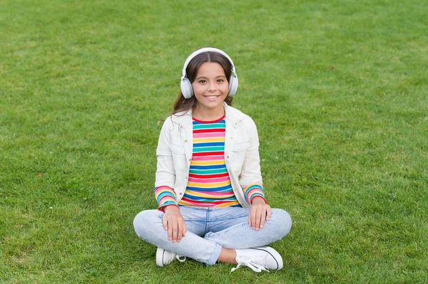 Yogacı kız. Kulaklık takan küçük bir çocuk. Yaz şarkı listesi. Bahar doğasının tadını çıkar. Çocuk sesli kitabı. Yeni teknoloji. Çocuk yeşil çimlerde müzik dinliyor. Sağlıklı yaşam tarzı ve rahatlama — Stok fotoğraf