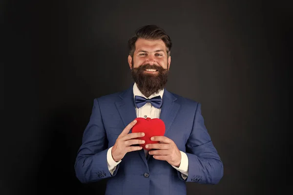 tuxedo man with red heart. love and romance. ready for date. brutal bearded hipster in formal outfit. confident and successful businessman in suit with bow tie. happy valentines day. Male shopping