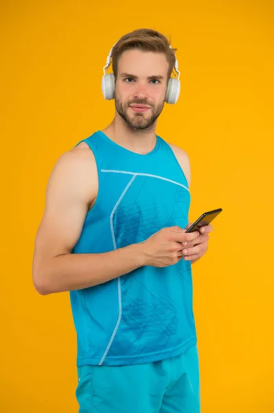 Τηλέφωνο για fitness fanatic. Ο γυμνασμένος ακούει μουσική στο κινητό. Χρήση εφαρμογών τηλεφώνου για αθλητική προπόνηση. Σύγχρονη ζωή. Νέα τεχνολογία. Ποιος χρειάζεται προσωπικό γυμναστή όταν έχεις έξυπνο τηλέφωνο; — Φωτογραφία Αρχείου