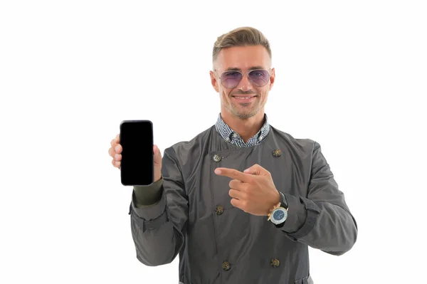 ¿Te gusta este teléfono? El hombre de negocios señala con el dedo el teléfono móvil. Un hombre guapo sostiene el teléfono aislado en blanco. Comunicación empresarial. 3G. 4G. Dispositivo móvil. Nunca estás solo con el teléfono celular — Foto de Stock