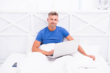 Bir şeyler alıp internetten alışveriş yapmak. Adam yatakta bilgisayar kullanıyor. İletişim ve insan konsepti. Çevik iş. Sabah titreşimleri. Adam dizüstü bilgisayarda çalışıyor. Online kurslar evde eğitim. İpuçlarını kilitle