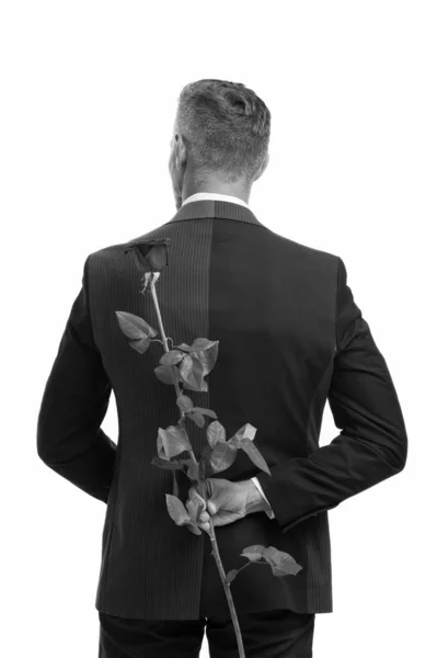 Sorpresa. Feliz día de San Valentín. moda formal masculina. el hombre guapo se escondió detrás de la espalda. preparar sorpresa para la cita romántica. Corbata negra para eventos formales. esmoquin con rosa. San Valentín secreto — Foto de Stock