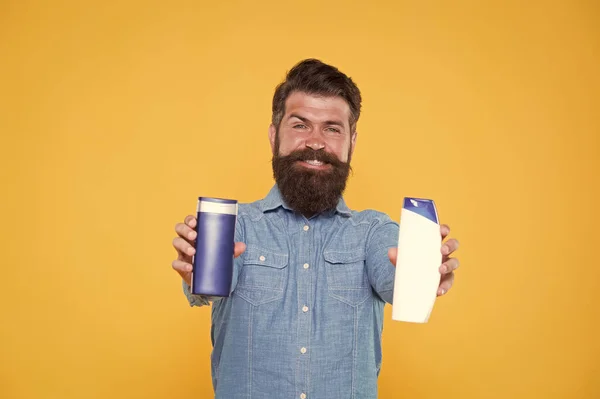 Essenziale per una buona igiene. Hipster tenere bottiglie di gel e shampoo. Uomo barbuto con prodotti per l'igiene. Cosmetici e articoli da toeletta. Abitudini igieniche personali. Igiene e salute — Foto Stock