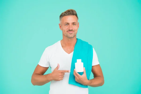 Um homem bonito com um frasco de comprimidos. tipo que apresenta frasco de gel. beleza masculina e saúde. rotina matinal diária. homem sem barba tem cabelo elegante ou corte de cabelo. pronto para tomar banho com toalha — Fotografia de Stock