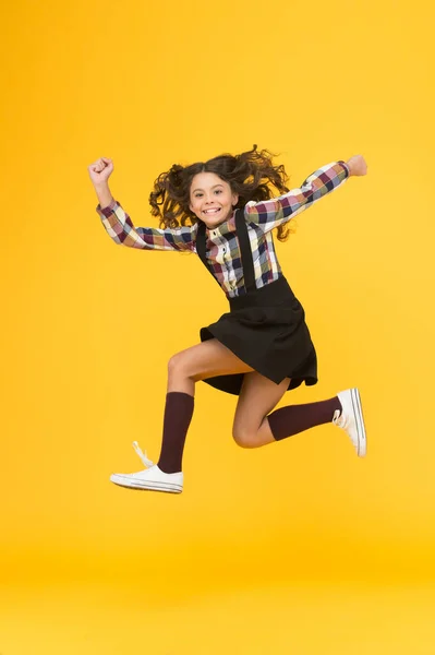 Énergie et ambition. Une fille énergique court à l'école. Joyeux enfant en plein milieu fond jaune. L'énergie de l'enfance. Maintien de l'énergie cinétique. La mode scolaire. Jeunesse et énergie — Photo