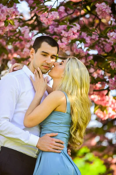 Loving people hug. Couple in love under sakura blossom. Love story. Passion concept. Man and woman in blooming garden. Couple spend time in spring tree garden. Couple in love under sakura blossom