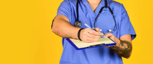 Enfermera escribiendo algunos datos en la carpeta de papeles. hospital masculino administrativo en un centro médico moderno. enfermera en abrigo médico con documentos escribe información importante. enfoque selectivo — Foto de Stock