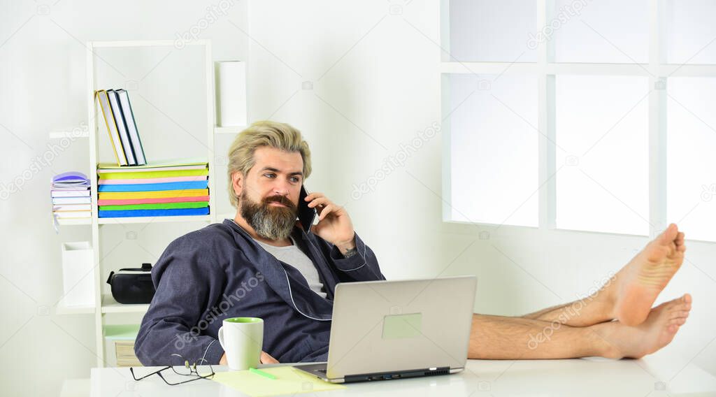 Business success. Technology. Handsome man using laptop at home. self quarantine routine. Serene barefoot guy resting, daydreaming at home. remote work with computer. networking while staying at home