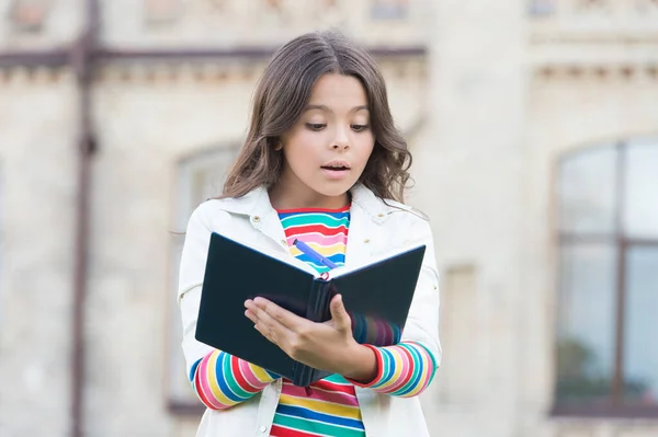 Utvecklar sina läskunskaper. Liten flicka läser bok utomhus. Liten unge gillar att läsa dag. Förtjusande bibliofil. Barnfantasi. Hemläsning. Skola och utbildning. Läsning gör henne smart — Stockfoto