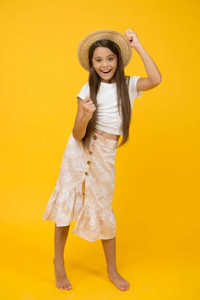 Vacanze estive. moda spiaggia estiva. felicità infantile. piccola ragazza indossare cappello di paglia. bambino allegro su sfondo giallo. vacanza e tempo di vacanza. festa divertente. bambino spensierato e felice a piedi nudi — Foto Stock