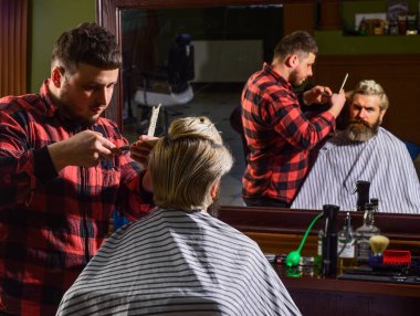 Uzun sarı saçlı adam, dikiz aynasından bakıyor. Kendini uyarılmış say. Hipster müşteri saçını kestiriyor. Berber makası. Saç kes. Berber, sakallı adam için kuaförlük yapıyor.