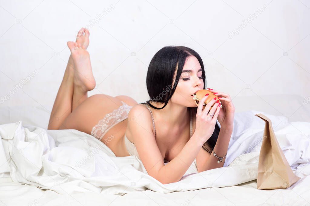 delicious beauty. erotic lingerie. breakfast in bed. Home delivery. woman with sexy fit body. girl eating burger in bed. willpower. morning relax. Dieting and temptation. sexy beauty. beauty in bed