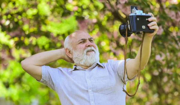 Auto-retrato. Memórias no estalo. Equipamento retrô para tirar fotos. Partilhando o seu conhecimento fazendo uma boa foto. Imitar as tendências da moda. Todos fotogénicos. Senior homem tomando selfie foto vintage câmera — Fotografia de Stock