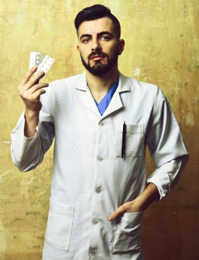 Sakallı doktor ve ciddi yüz ifadesi hapları tutuyor.