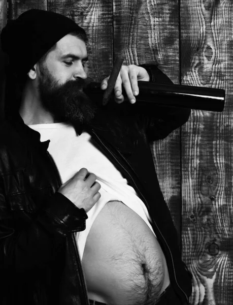 Skäggig brutal kaukasisk hipster som håller flaska och röker cigarr — Stockfoto
