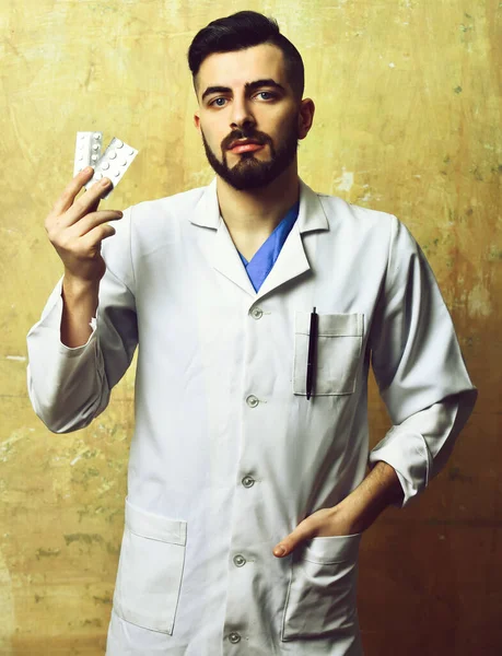 Sakallı doktor ve ciddi yüz ifadesi hapları tutuyor.