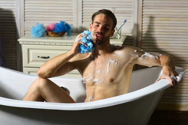 Küvette süngerle yıkanan köpükle kaplı maço.