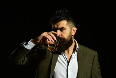 Elinde bir bardak alkol tutan takım elbiseli ciddi bir adam.