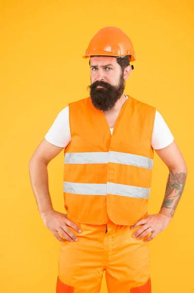 Man i byggbranschen. Arbetare gul bakgrund. Skäggig man i hård hatt och skyddsväst. En skicklig man med skägg och mustasch. Renovering och reparation. Byggande och byggande — Stockfoto