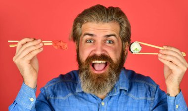 Suşi siparişi. Sushi teslimatı. Mutlu adam suşi yer. Çubuklu suşi ve zencefil. Japon mutfağı. Japonya 'da geleneksel yiyecekler. Şef yemek servisi. Asya yemeği