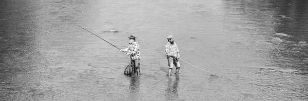 Sommerwochenende. Glücklicher Fischer mit Angel und Netz. Hobby und sportliche Aktivität. Gemeinsam angeln. Männer stehen im Wasser. Angeln ist viel mehr als Fisch. Männerfreundschaft. Vater und Sohn angeln — Stockfoto