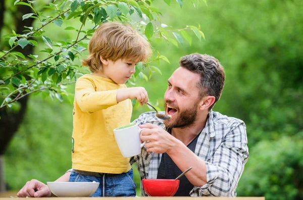This is for you. healthy food and dieting. Childrens day. happy fathers day. Little boy with dad eat cereal. family dinner time. father and son eating outdoor. summer picnic. Morning breakfast — Stock Photo, Image