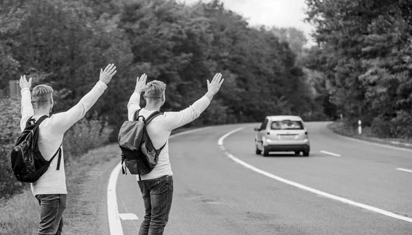 Just friends and road ahead. feel the freedom. Travelling with friends. Travel by autostop. Hopeless hitchhiker. Men try stop car. twins walking along road. hiker man on road. Way of travelling — Stock Photo, Image