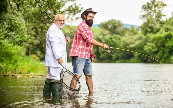 Dinero atrayendo ideas. amigos hombres con caña de pescar y red. padre jubilado e hijo barbudo maduro. pescadores felices. Buena ganancia. hobby del hombre de negocios. pesca de jubilación. Aventuras de pesca con mosca —  Fotos de Stock