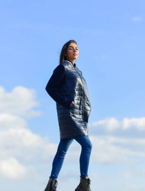 Yalnız yürüyorum. Mavi gökyüzü arka planında bir kadın. Kış tatili Uzun ceket. Hayalperest kız. Genç ve özgür bir kavram. Kıyafetlerinden daha fazlasını bekle. Kadınlar açık havada havadan hoşlanır. Güzellik ve moda