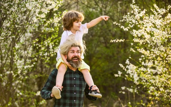 Família feliz. Pequeno filho. Passeio de primavera. Paternidade. Dia dos pais. Menino e pai no fundo da natureza. Hipster e filhote no jardim florescente. Homem brutal barbudo bom pai. Pai e filho — Fotografia de Stock