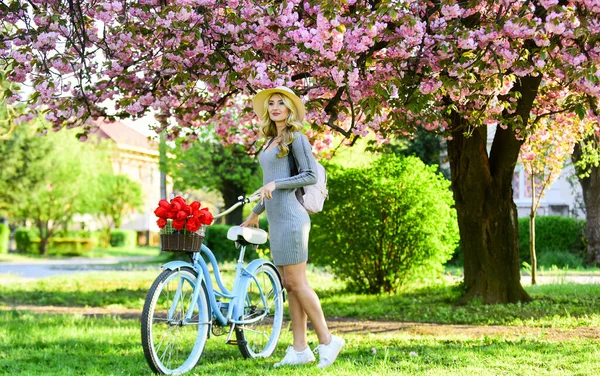 Aktivtag. Kirschbaum rosa Blüte. perfekter Geruch. Parfüm-Spa und allergisch. Reisen. Retro-Frau verkauft Tulpenblumenstrauß. Mädchen unter Sakura mit Oldtimer-Fahrrad. Schönheit und Mode im Frühling — Stockfoto