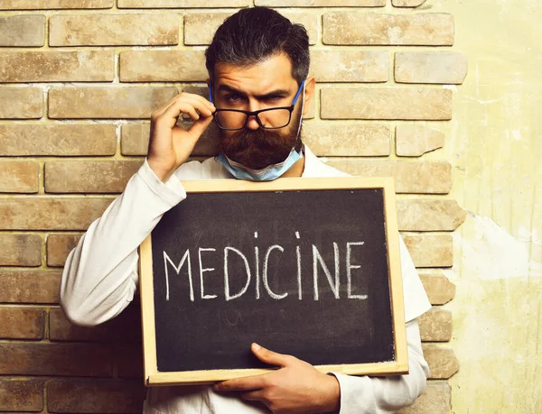 Brutalny, biały lekarz trzymający deskę z napisem "Lekarstwo" — Zdjęcie stockowe