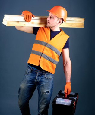 Marangoz, marangoz, marangoz, işçi, çalışkan suratlı müteahhit omuzlarında tahta kirişler taşıyor. Ormancılık konsepti. Adamım, kasklı tamirci, kasklı kasklı alet çantası, tahta kirişler, gri arka plan..