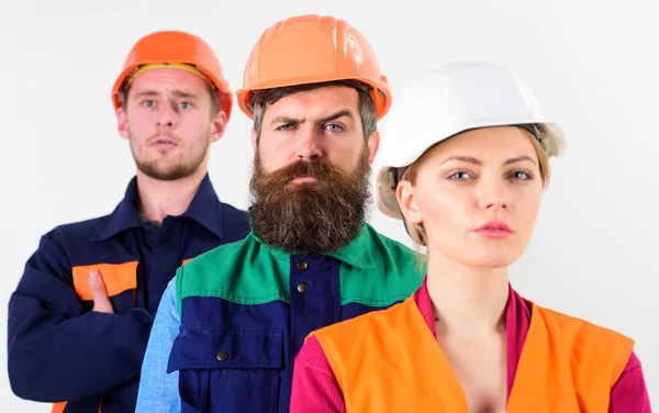 Equipo serio de tres trabajadores constructores en sombreros duros —  Fotos de Stock