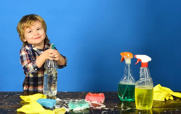 Cleaning activities concept. Child near table with cleaning supplies on. — Stock Photo, Image