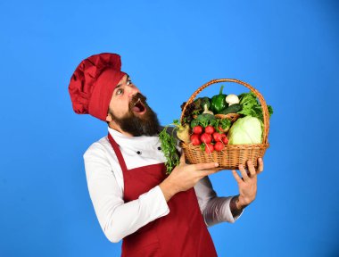 Burgonya üniformalı heyecanlı yüzlü aşçı sebze tutar.