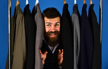 Moda seçimi konsepti. Tezgahtar ya da satıcı takım elbiselilerin arasına saklanır